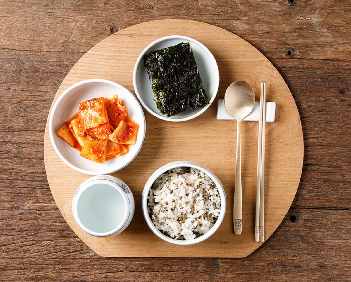 쌀과 검은보리를 함께 섞은 밥한공기가 있고, 그 옆에 나란히 수저와 젓가락이 놓여져있다. 그리고 그 주변에 김과 무석박지가 접시에 담아져있다.