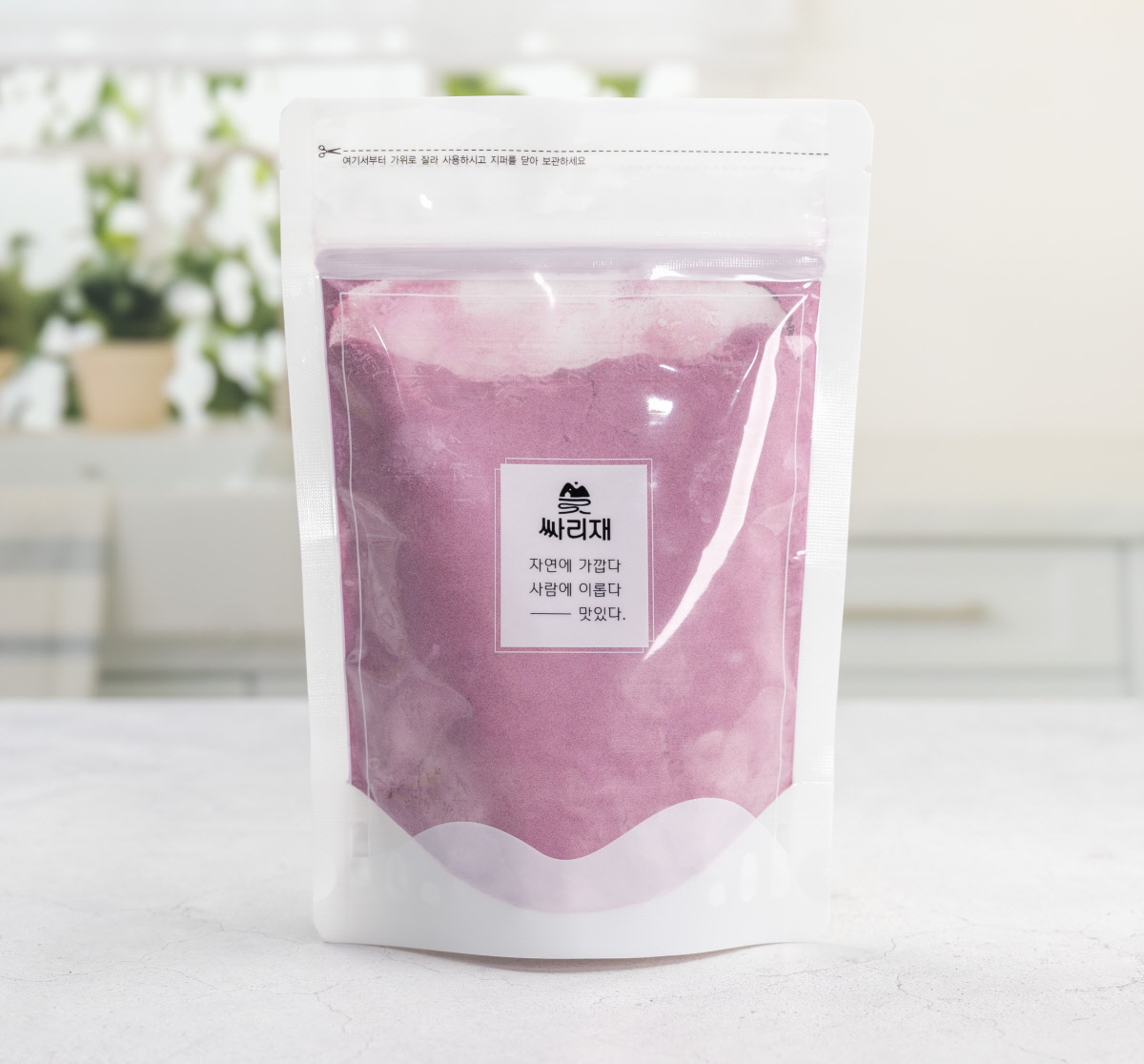 싸리재 구운 자색고구마분말 300g 제품이 투명 지퍼백에 포장된 모습으로, 전면 라벨에는 ‘자연에 가깝다 사랑에 이롭다 맛있다’ 문구가 적힌 깨끗한 주방 배경