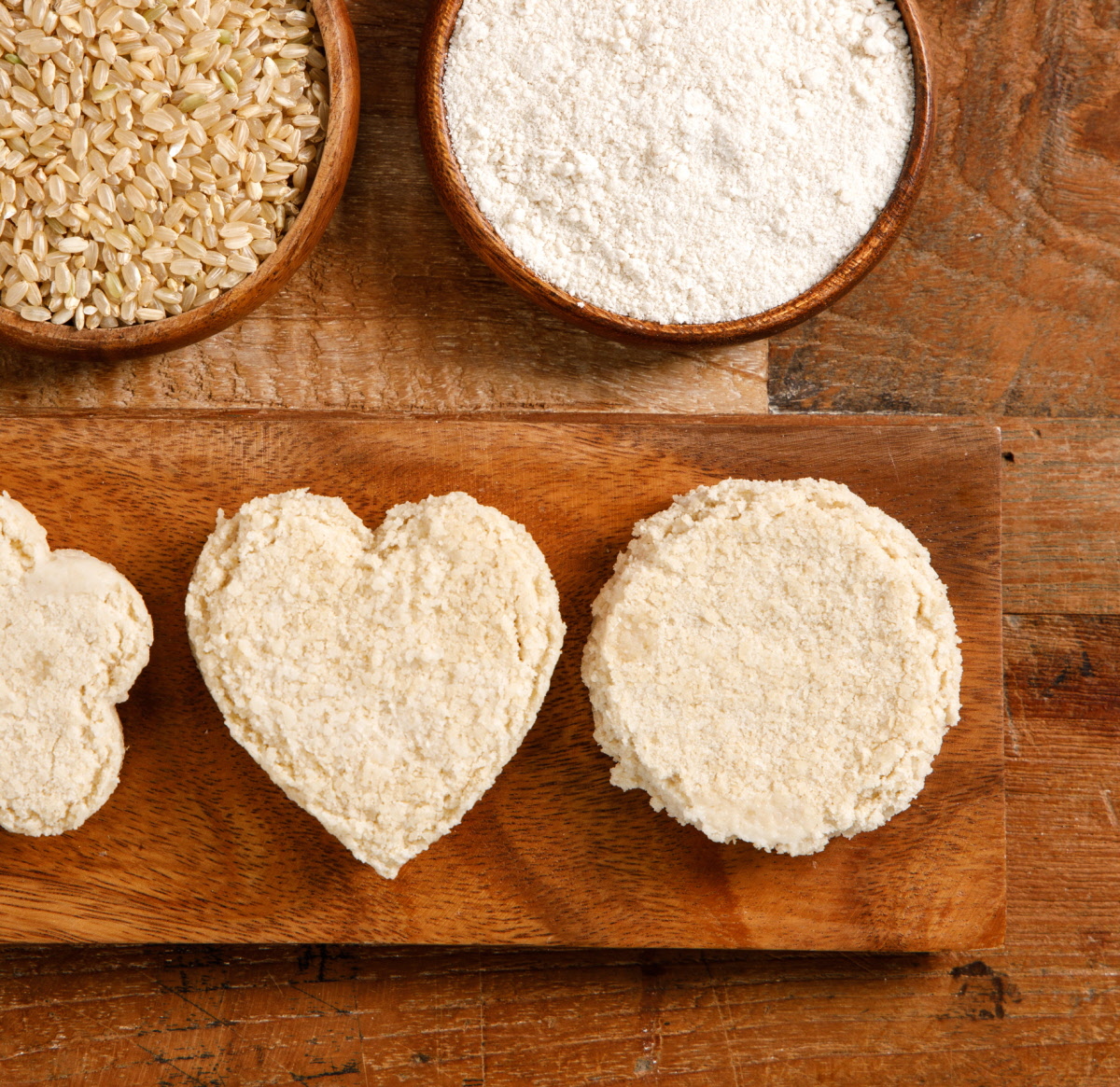 나무 도마 위 유기농현미 쌀과 가루 및 하트와 원형으로 쪄낸 유기농떡