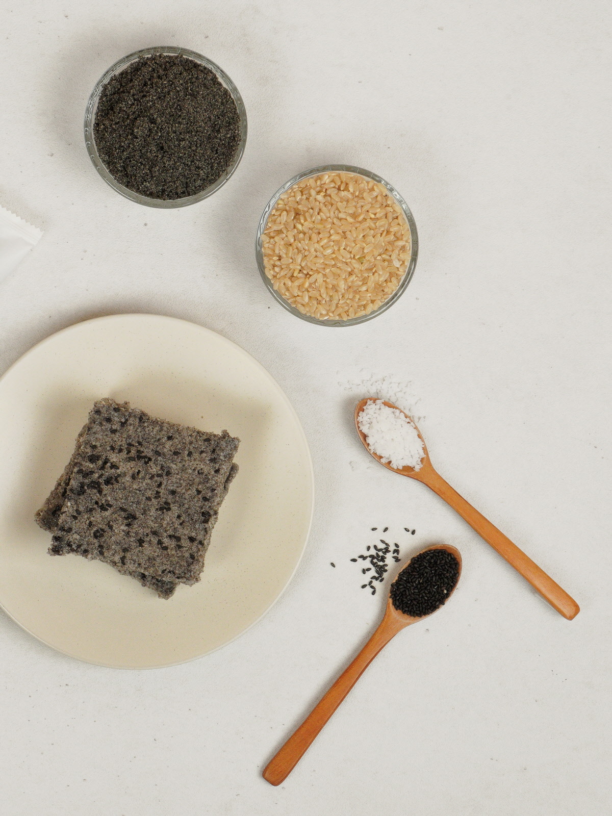 접시 위에 놓인 흑임자현미설기와 원재료인 유기농현미멥쌀, 흑임자깨, 흑임자가루, 천일염의 모습