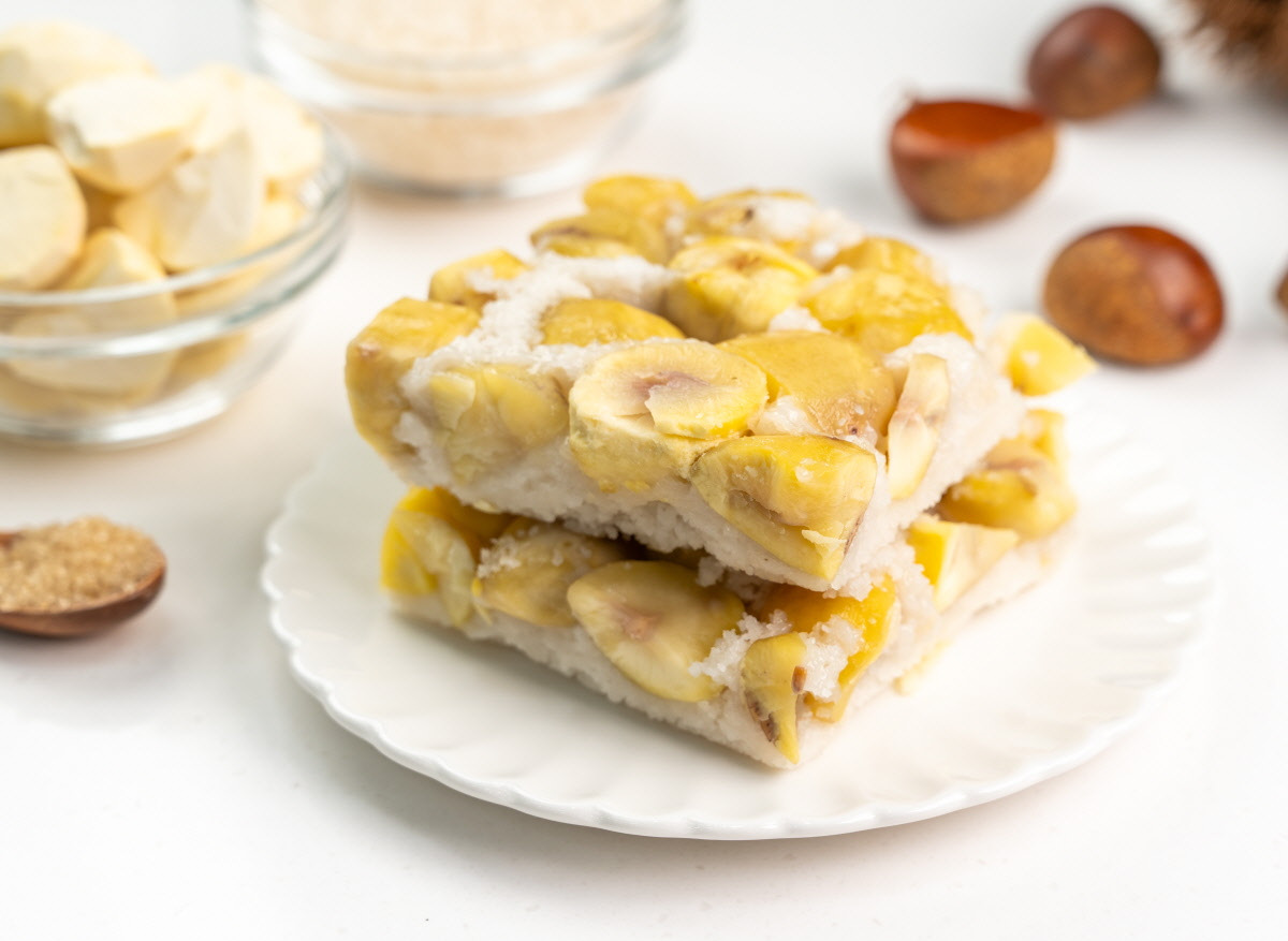 밤설기 설기떡 접시에 두 겹으로 올린 조각에서 큼직한 알밤이 가득 박혀 있고 주변에 국산밤과 유기농 설탕, 소금이 배경에 놓인 건강간식 연출