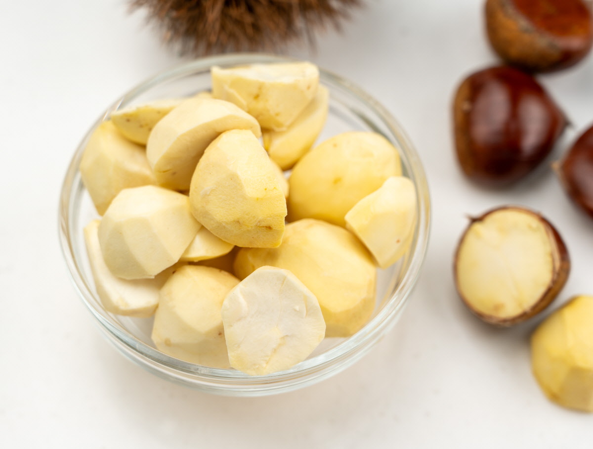 껍질을 벗긴 신선한 국산 생밤을 유리볼에 담아 밝은 조명 아래 노란빛 단면이 선명하게 보이는 재료 클로즈업 컷