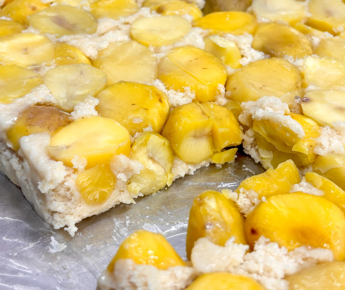 찜기에서 갓 꺼낸 밤설기를 네모난 조각으로 썰어낸 장면으로, 윤기 나는 밤 알갱이와 고운 떡결이 조화를 이룬 완성단계 클로즈업