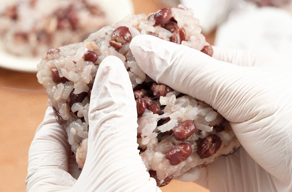 위생 장갑을 끼고 찰진 팥 찰밥을 반으로 갈라 쫀득한 질감을 보여주는 모습