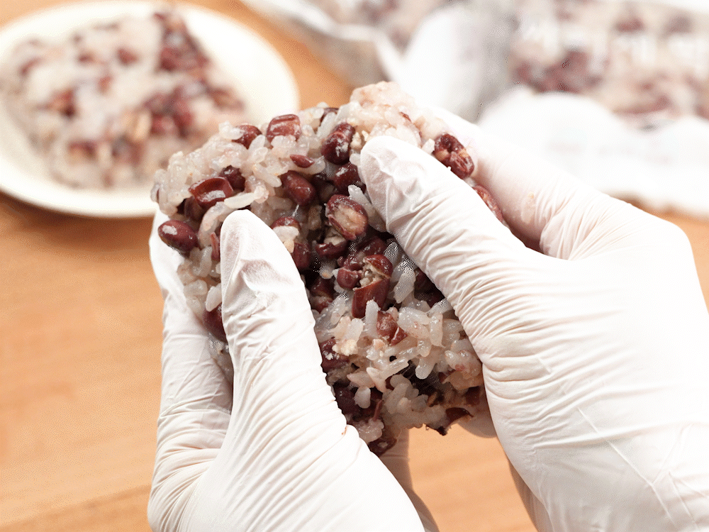 두 손으로 팥 찰밥을 천천히 떼어내며 부드럽고 쫀득한 찰기를 극대화한 영상