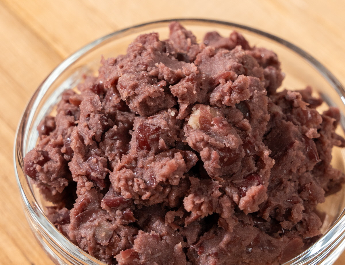 앙금쑥개떡 싸리재 개떡 속에 들어가는 통팥앙금을 유리볼에 가득 담아 가까이 보여주는 모습으로 으깬 팥알의 질감과 진한 팥빛이 선명하게 드러난 구성