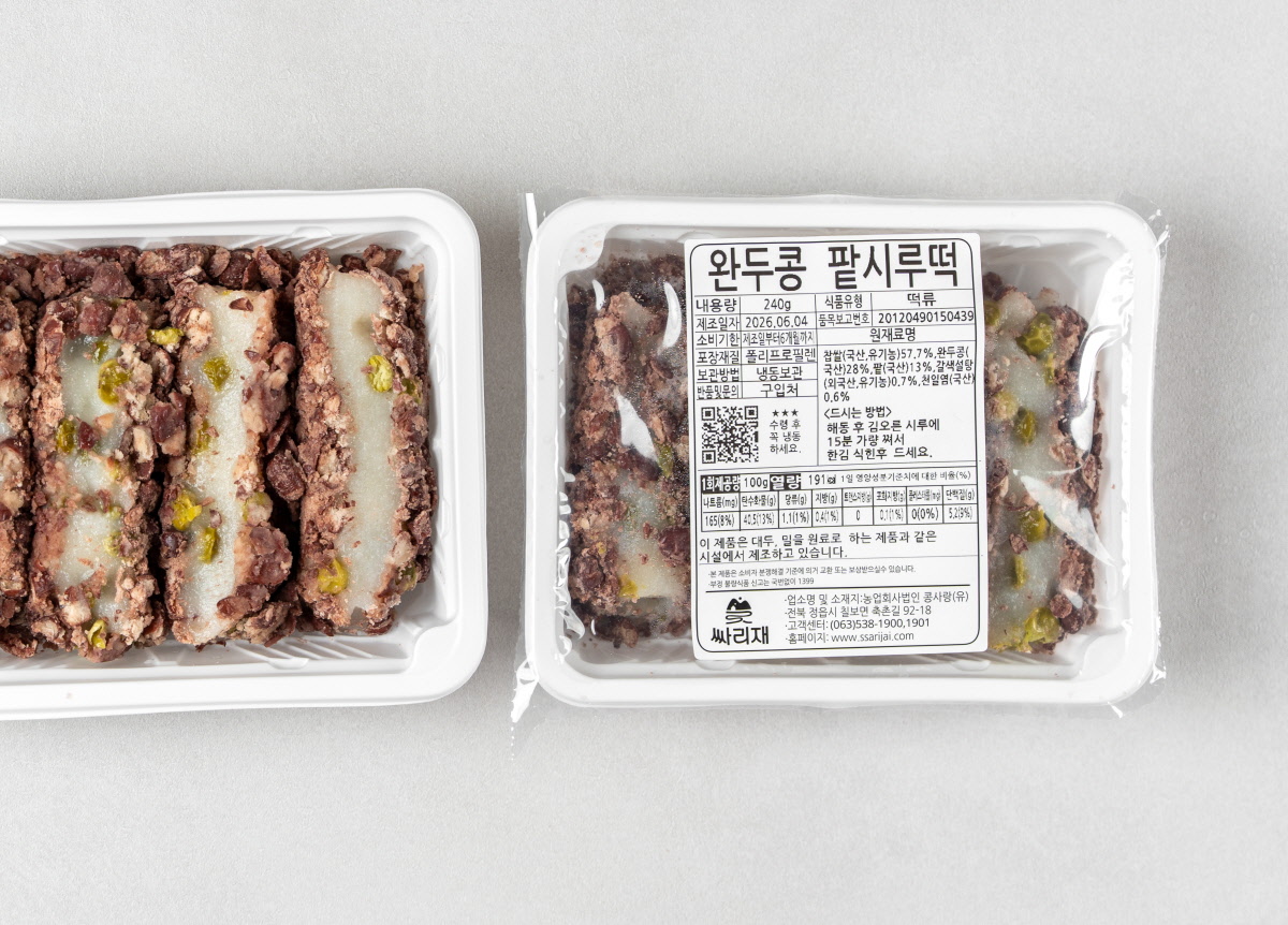 완두콩 고물이 박힌 팥시루떡의 내부와 외부 패키지 모습입니다. 왼쪽 용기에는 큼직하게 썰린 찰진 떡 네 조각이 단면을 드러내고 있으며 오른쪽 용기는 비닐로 밀봉된 채 완두콩 팥시루떡 라벨이 붙어 있습니다.