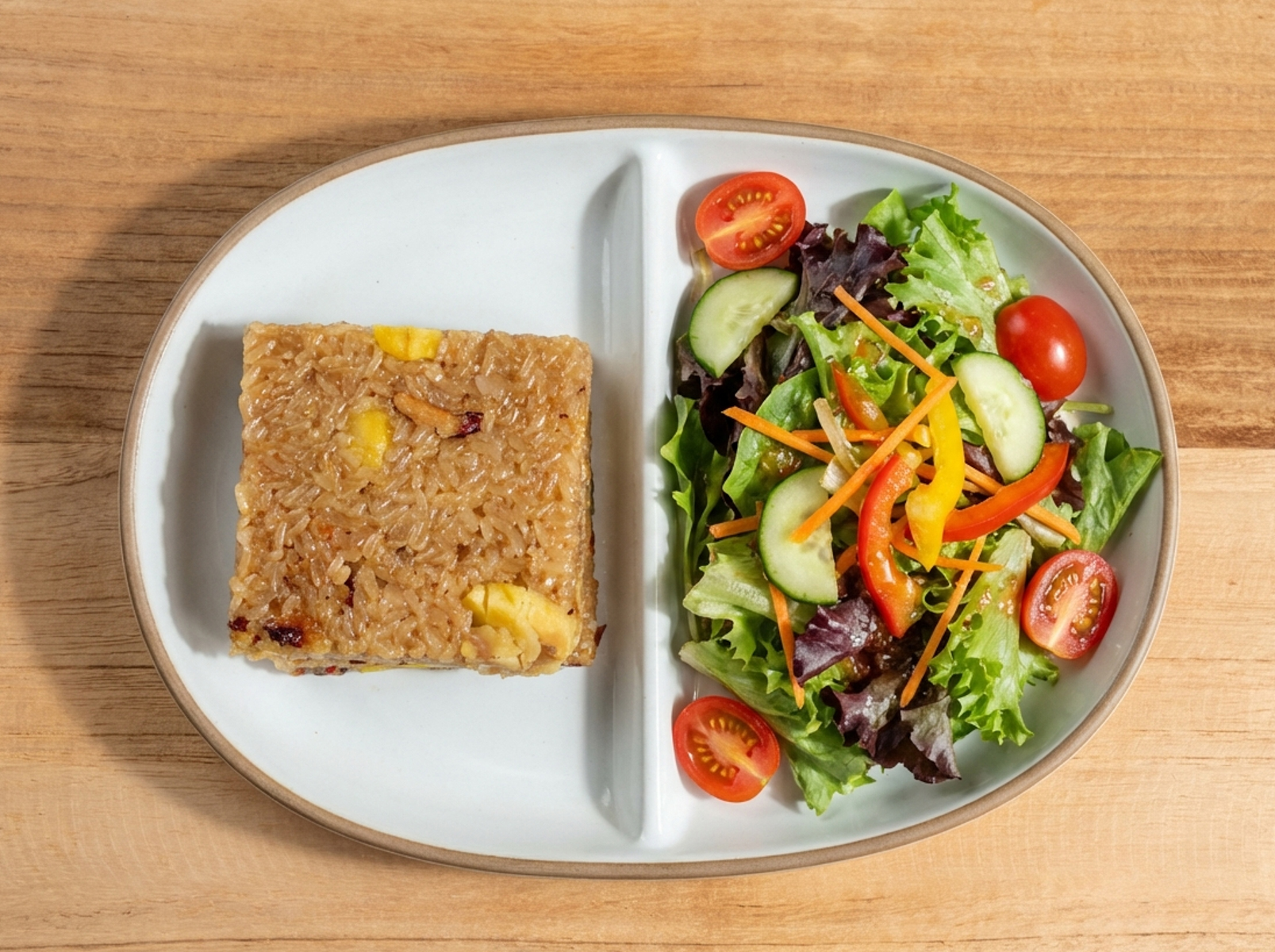 집밥 간편식 구성처럼 나뉜 접시에 네모난 약밥 한 조각과 샐러드가 함께 담겨 있고 방울토마토 오이 채소가 곁들여진 한 끼 플레이팅