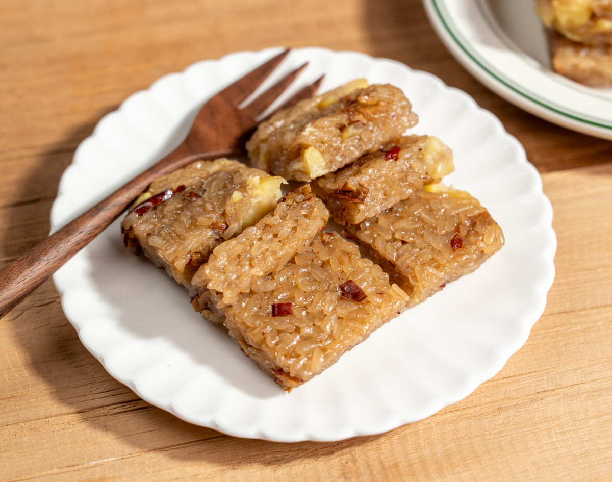 아이간식으로 집어 먹기 좋게 길쭉하게 자른 미니 약식 여러 조각이 흰 접시에 담겨 있고 나무 포크가 함께 놓인 모습