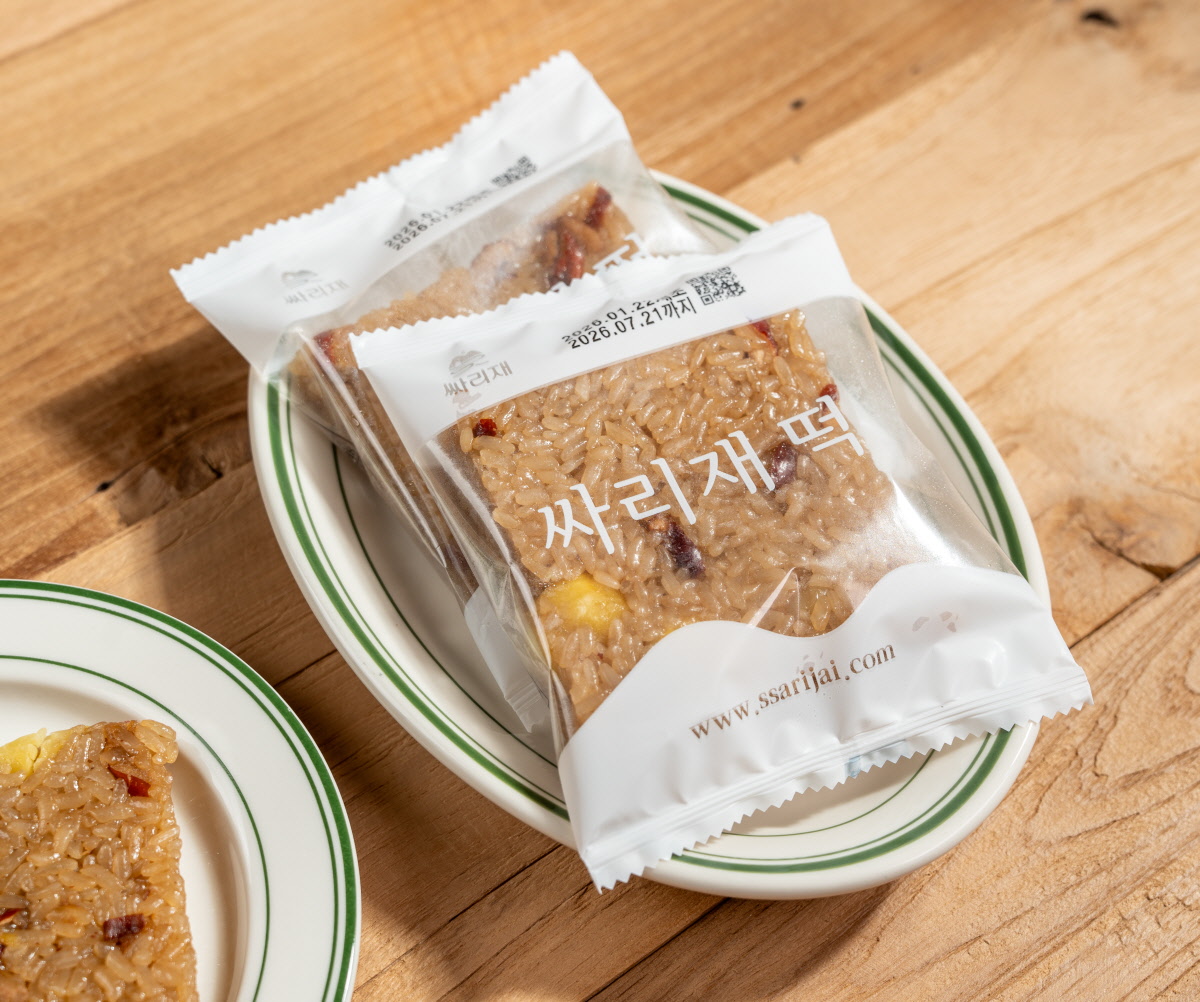 답례떡 포장 느낌의 개별 포장 미니 약식이 접시 위에 올려져 있고 포장지에 싸리재 떡 글자와 www.ssarijai.com 표기가 보이는 모습