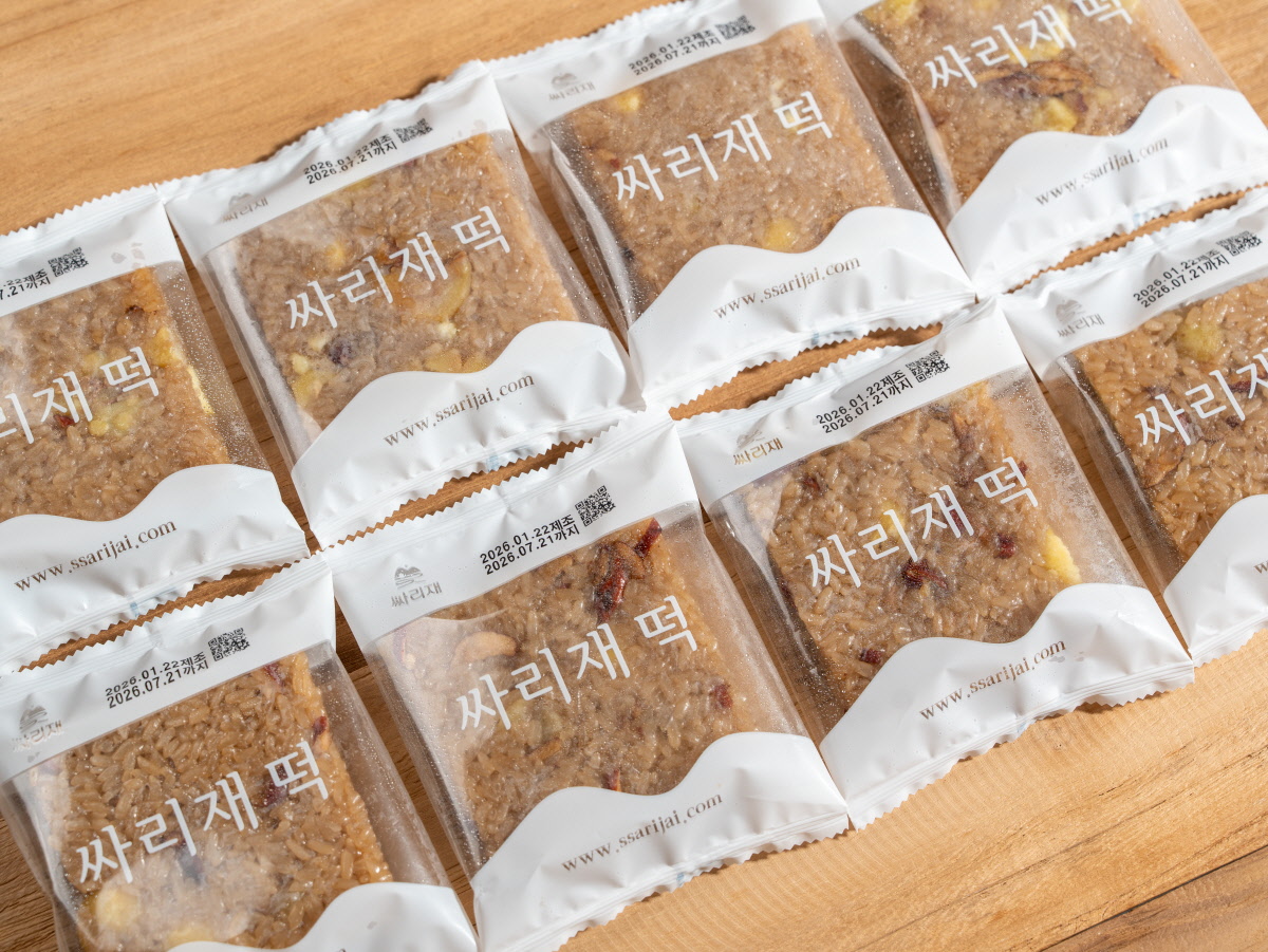 미니 약식 답례떡으로 쓰기 좋은 개별 포장 약밥이 여러 개 가지런히 놓여 있고 포장지에 싸리재 떡 글자가 반복되어 보이는 모습