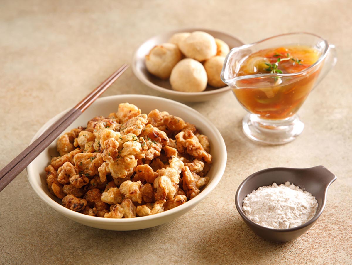 탕수육 요리와 탕수육 소스를 담은 그릇이 올려져 있고 주변에 쌀가루를 담은 접시가 놓여져 있다.