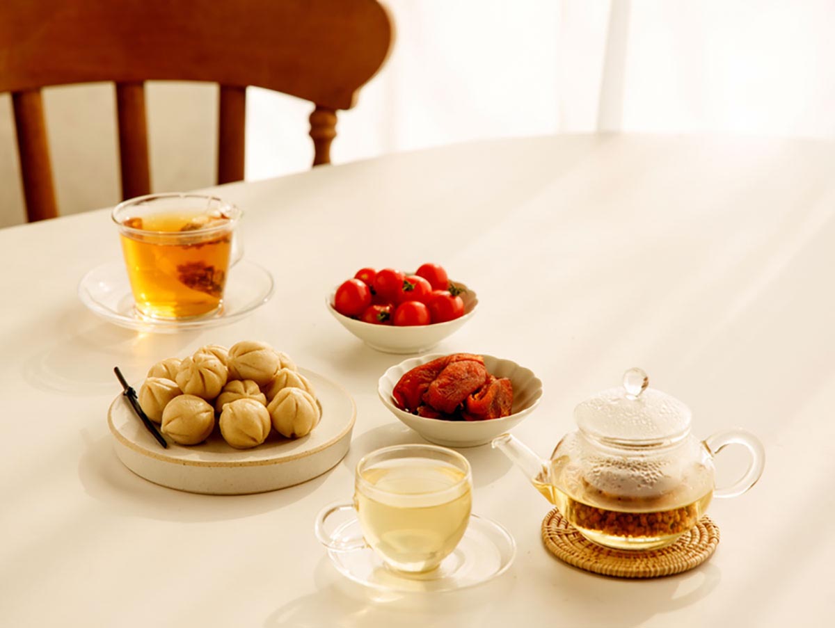 식탁 위에 꿀떡과 방울토마토, 곶감을 작은 접시에 각각 담아 놓고 옆에는 현미차를 우린 주전자와 컵이 있다
