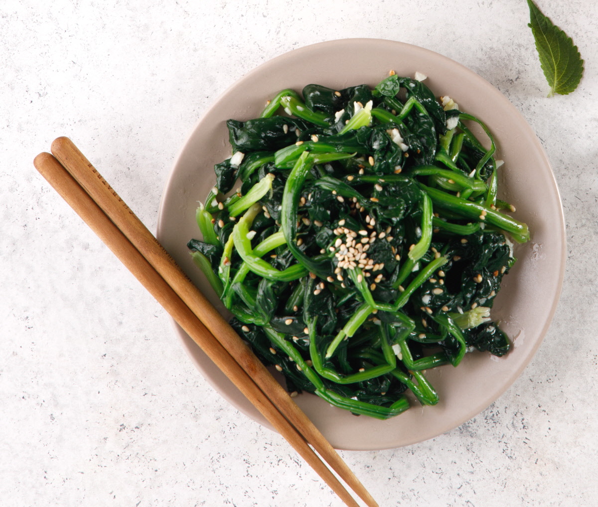 접시 위에 시금치 참깨무침이 푸르게 올려져 있고, 위에 고소한참깨와 볶은참깨를 솔솔 뿌려 참깨나물 반찬의 향과 식감을 살린 모습.