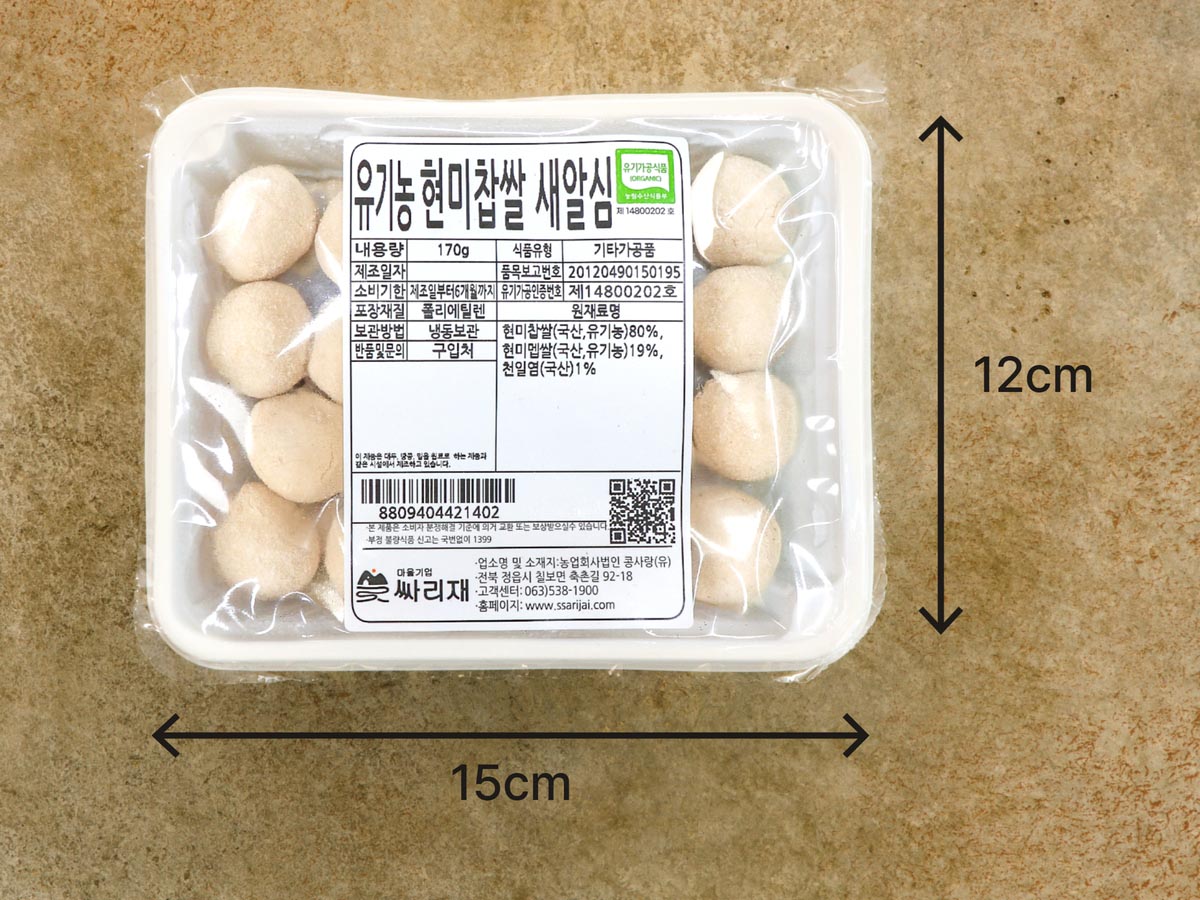 가로 15cm, 세로 12cm의 흰색 사각 플라스틱 그릇에 둥그런 새알심이 담겨져 있고, 그 위를 비닐 뚜껑으로 덮어 포장한 모습입니다. 비닐 뚜껑에는 상품설명이 적힌 스티커가 붙여져 있습니다. 다음은 스티커의 내용입니다. 제품명 현미찹쌀 새알심, 내용량 170g, 식품유형 기타가공류, 보관방법 냉동보관, 유통기한 제조일로부터 6개월까지, 반품 및 문의 구입처, 포장재질 폴리에틸렌, 원재료 및 함량 현미찹쌀(국산, 유기농) 80%, 현미멥쌀(국산, 유기농)19%, 천일염(국산)1%. 업소명 및 소재지 농업회사법인 콩사랑(유), 전북 정읍시 칠보면 축촌길 92-18, 고객센터 063 538 1900, 홈페이지 www.ssarijai.com. 본제품은 소비자 분쟁해결 기준에 의거 교환 또는 보상받으실 수 있습니다. 부정 불량식품 신고는 국번없이 1399. 품목보고번호 20120490150195