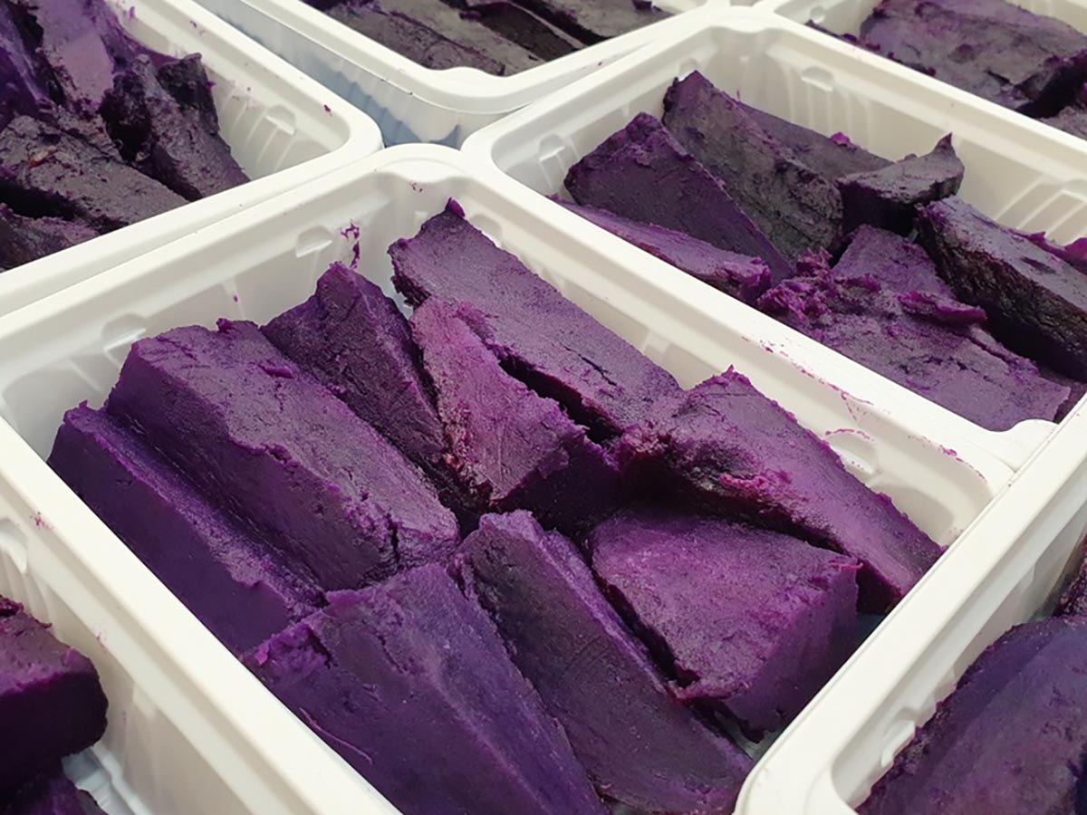 일정한 크기로 잘라 포장된 자색고구마 조각들이 하얀 용기에 가지런히 담긴 모습으로, 오븐에 구운 후 급속 냉동한 천연 간식의 보라색 빛깔이 강조됨