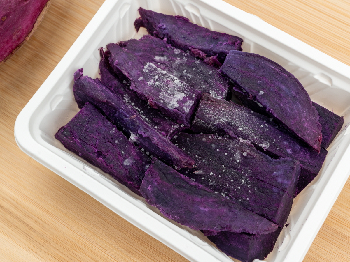 잘게 썰어 흰 용기에 담긴 자색고구마 조각으로, 부드럽고 단단한 질감이 함께 느껴지는 오븐구이 스타일의 천연 보라색 간식