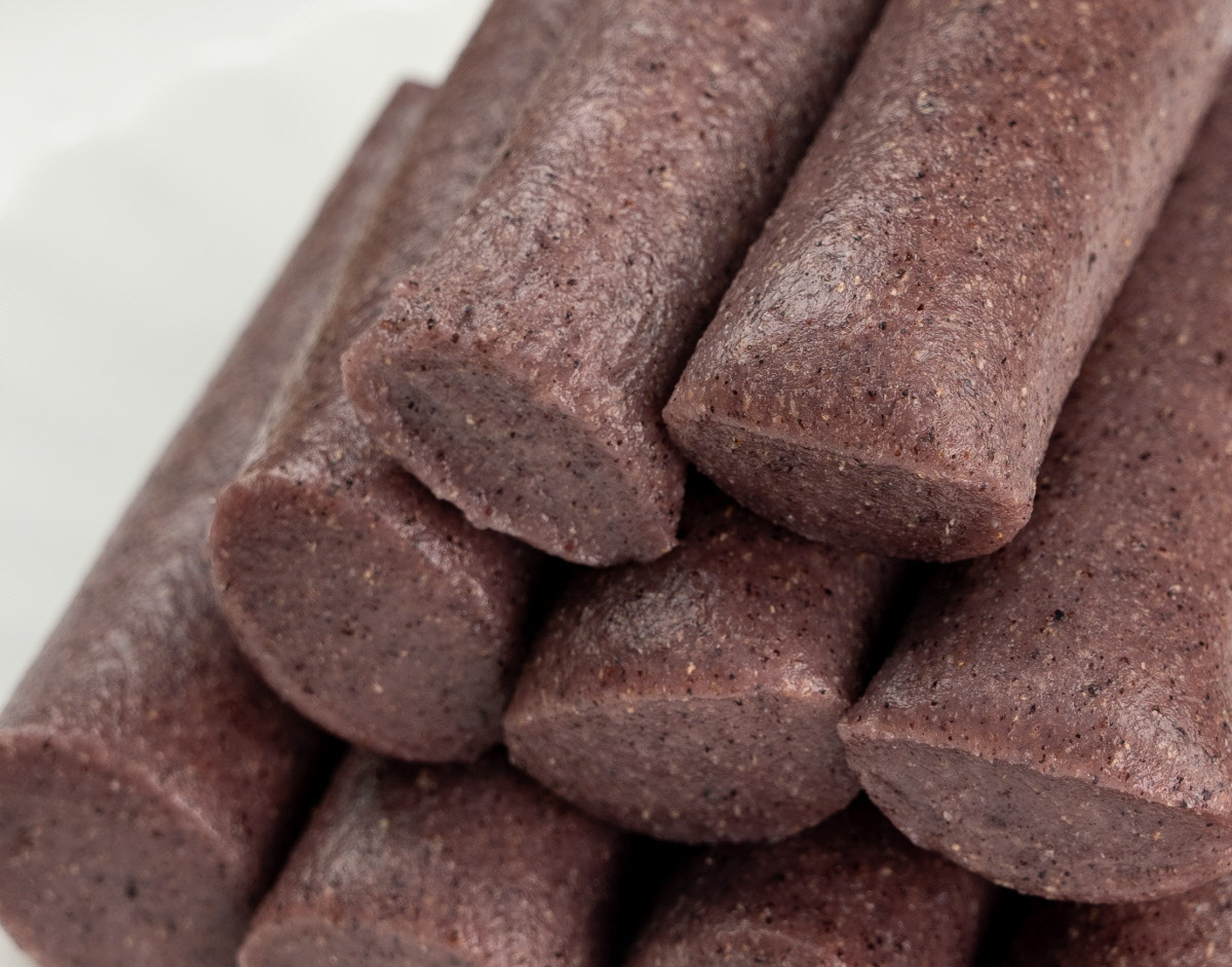 투명 개별포장에 담긴 흑미 가래떡을 손에 들고 있는 모습으로, 신선한 제조일자와 포장 디자인이 깔끔한 인상을 주며 아침대용떡으로 적합한 건강식임을 표현한다.