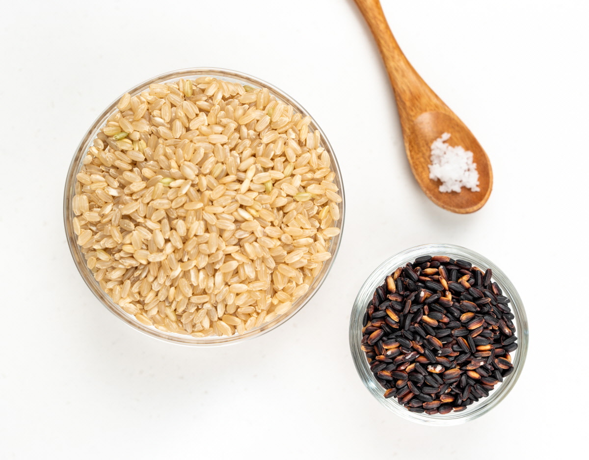 유리볼에 담긴 유기농 현미와 흑미, 그리고 나무숟가락의 천일염이 함께 놓인 장면으로, 무첨가떡에 사용된 재료의 자연스러움과 정직함을 강조한다.