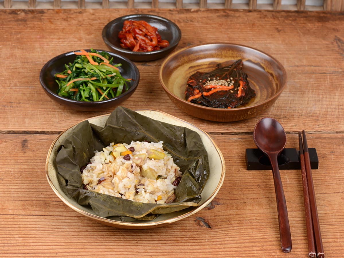 나무 테이블 위에 연잎밥과 반찬 장아찌로 상차림한 모습