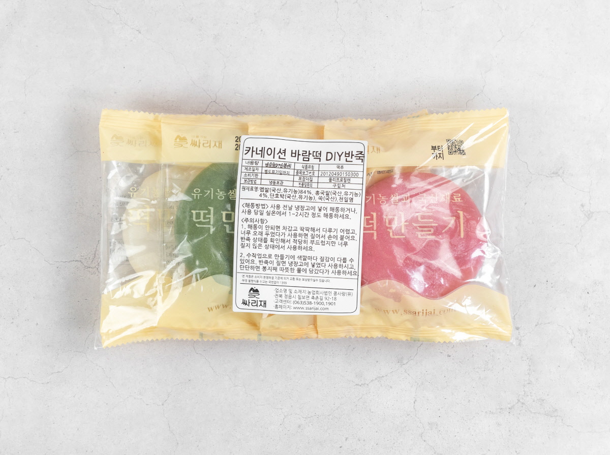 4가지 색상의 카네이션말랑떡 반죽이 투명 포장에 담겨 있고, 제품 라벨에는 유기농 원료와 사용 방법이 표기되어 있음