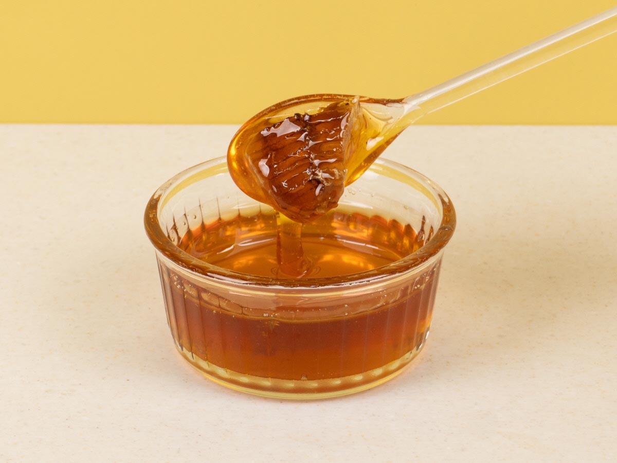 토종꿀의 색과 질감을 보기위한 유리그릇에 담긴 꿀을 스푼으로 뜬 모습