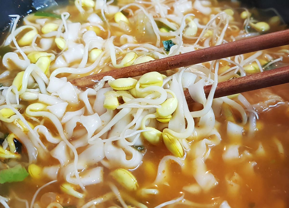 집에서 키운 콩나물콩으로 김치 칼국수를 끓여 젓가락으로 들려고 하고 있다.