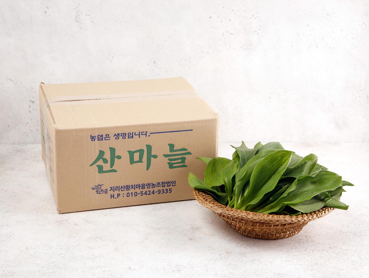 산마늘을 담은 종이 박스와 산마늘잎을 담은 소쿠리가 나란히 있는 장면