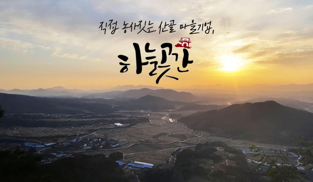 장수 안양마을을 높은 곳에서 찍은 마을 전경 사진입니다. 작은 마을이 겹겹이 펼쳐진 낮은 산들을 둘러업고 있는 모습입니다. 마을 중앙에는 여러 채의 민가들이 모여 있고, 그 주변으로 초록빛 논과 밭이 둘러싸고 있습니다. 하늘에는 주황빛 노을이 지는 모습입니다.