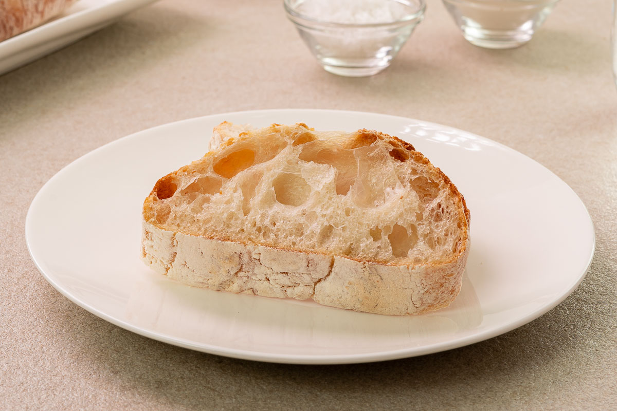플레인 치아바타 파베이크를 썰어 한 조각을 하얀 접시 위에 올려놓은 모습