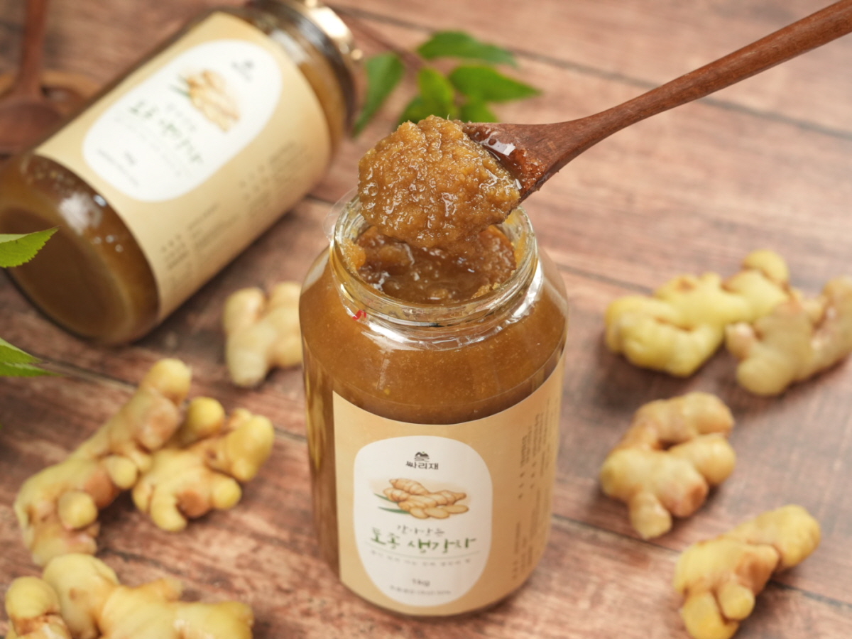 토종 생강청을 유리병에서 숟가락으로 떠올리는 장면. 차로 바로 우려내기 좋은 질감의 생강차 베이스가 깔끔한 배경과 함께 강조됨.