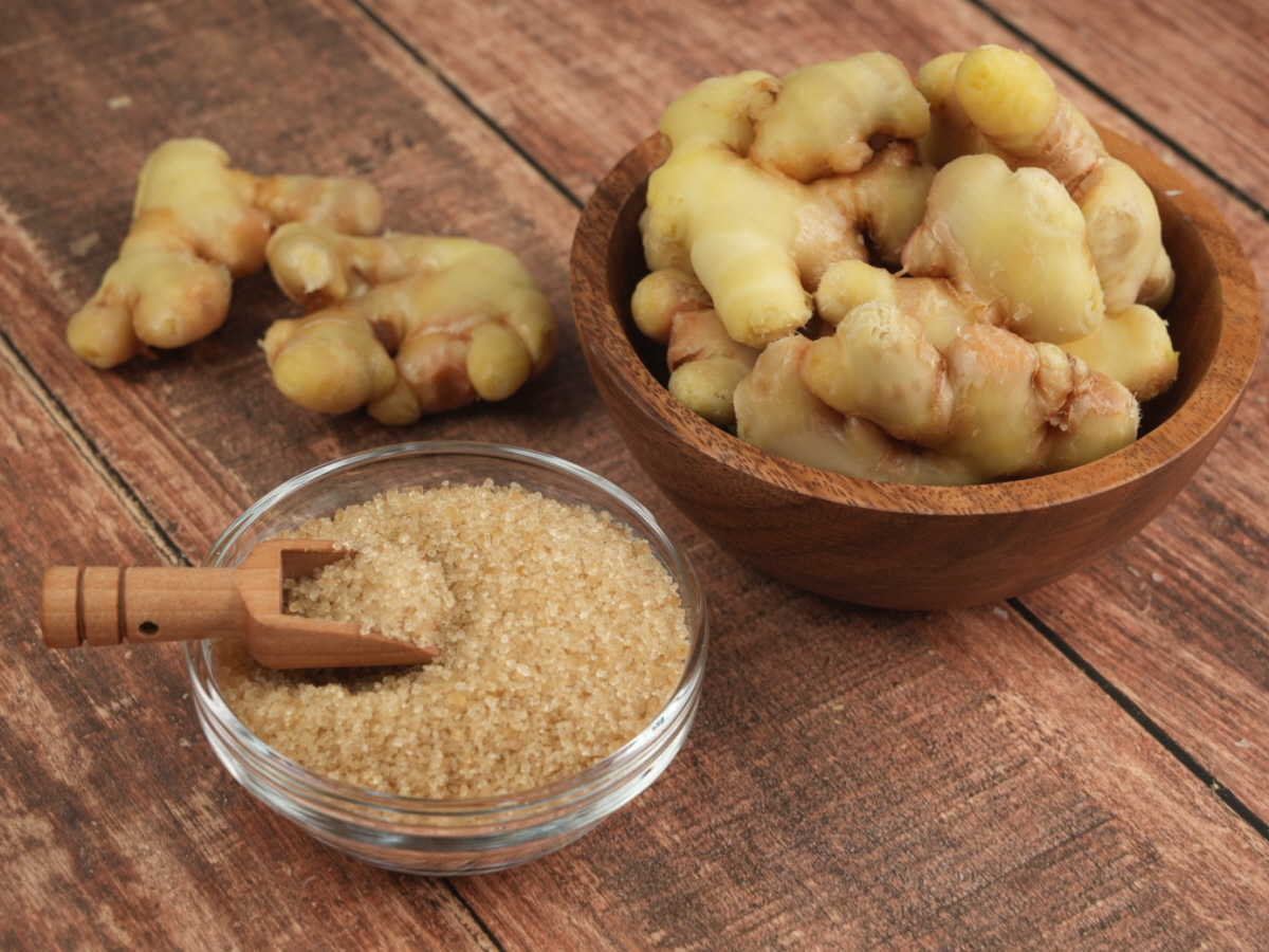 도자기 접시 위에 놓인 껍질이 있는 생강과 황설탕. 생강차 만드는 방법에 쓰이는 기본 재료의 조합을 강조.