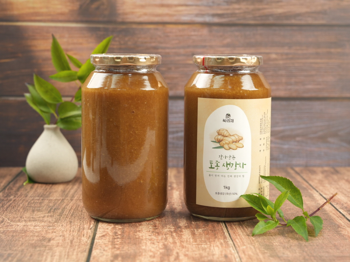 뚜껑을 닫은 유기농 생강차 유리병과 생강차 음료 두 잔이 함께 놓인 장면. 라벨에는 ‘유기농 생강차’ 문구가 선명하게 보임.